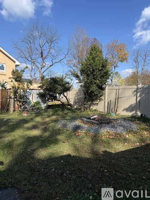 A backyard with a tree, a fence, and a house.