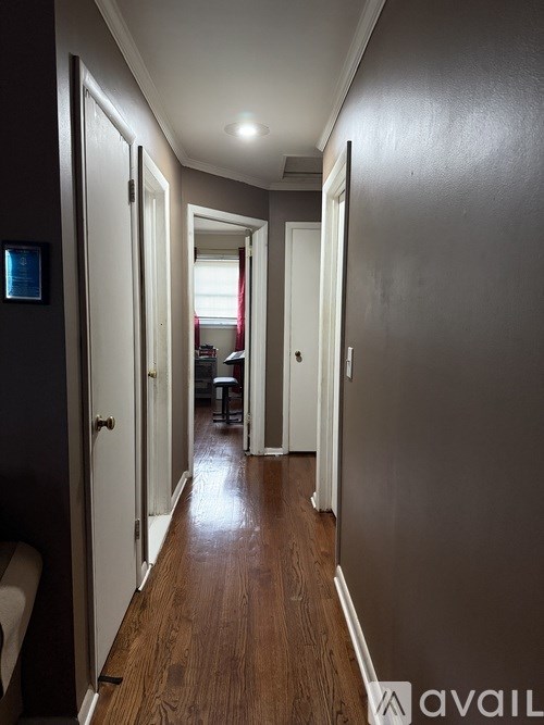A long hallway with doors on both sides and a bench on the left.