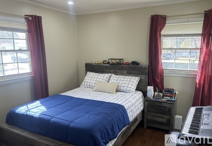 A bedroom with a blue bedspread and a piano.