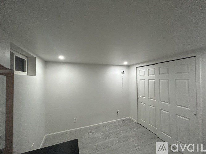 A room with a white door and a window on the left side.