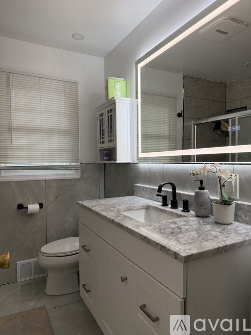 A bathroom with a marble countertop and a large mirror.
