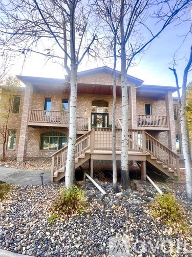 A house with a balcony and a porch surrounded by trees.