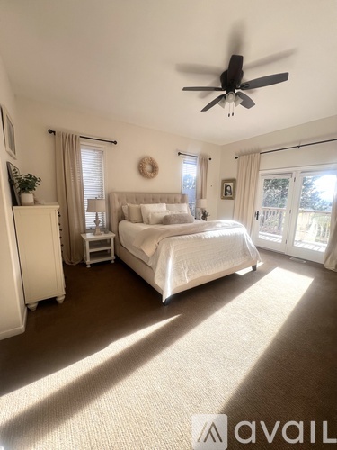 A bedroom with a large bed and a ceiling fan.