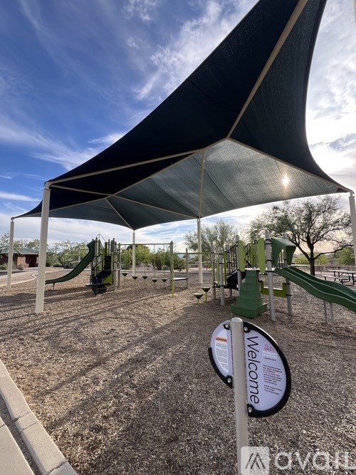 A playground with a black canopy and a green slide.