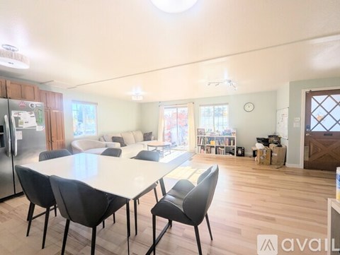 A kitchen with a table and chairs in the foreground and a refrigerator on the left.