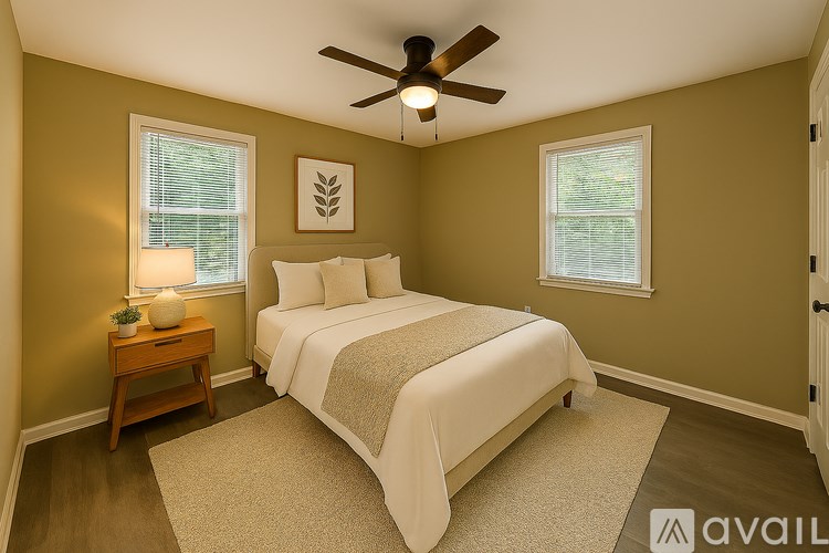 A bedroom with a bed, a ceiling fan, and a nightstand with a lamp.