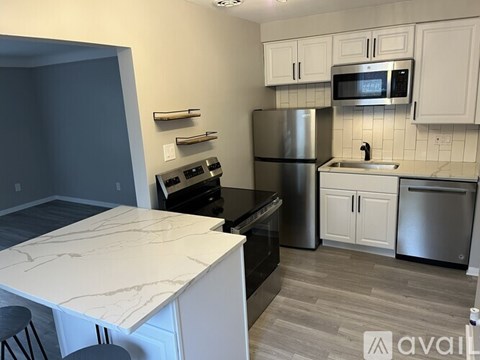 A kitchen with a white counter top and stainless steel appliances.