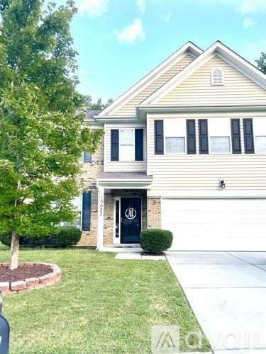A two-story house with a black front door and a small tree to the left.