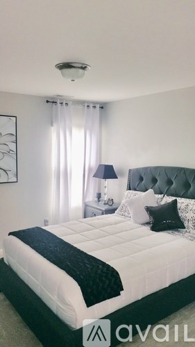 A bedroom with a large bed and a lamp.