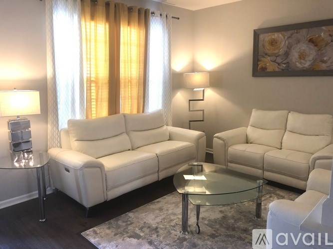 A living room with white furniture and a glass table.
