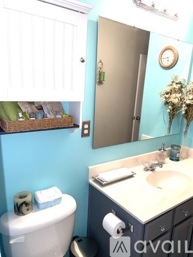A bathroom with a toilet, sink, and mirror.