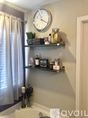 A bathroom with a shelf and a clock on the wall.
