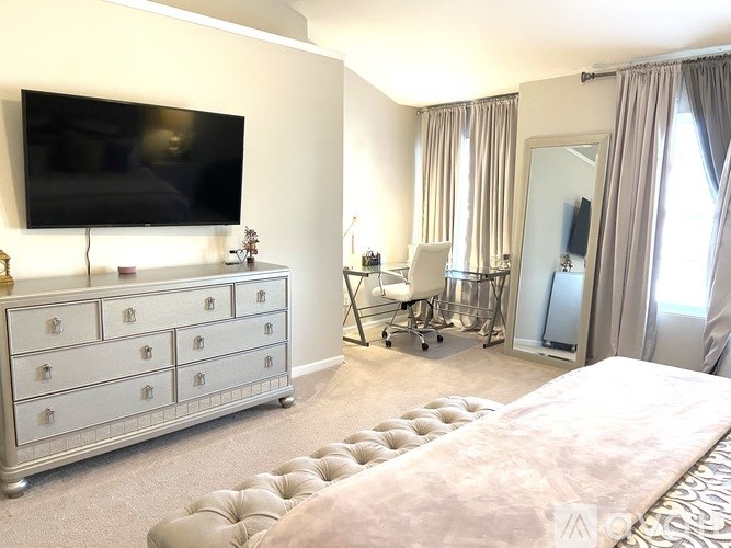 A bedroom with a large bed, a dresser, and a television.