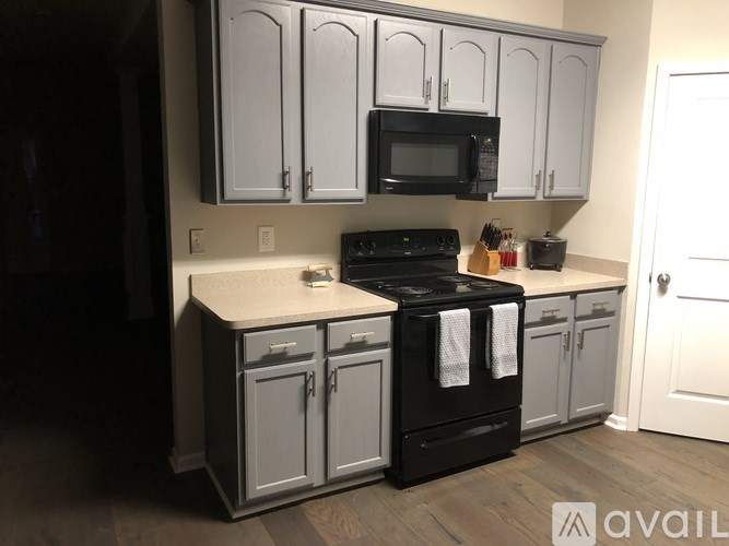 A kitchen with a black stove top oven and a microwave above it.