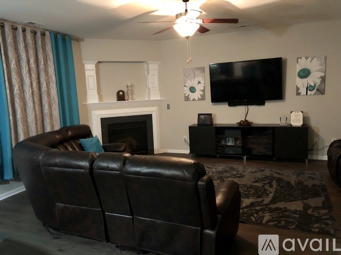 A living room with a black leather couch and a fireplace.