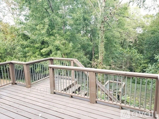 A wooden deck with a metal railing overlooks a wooded area.