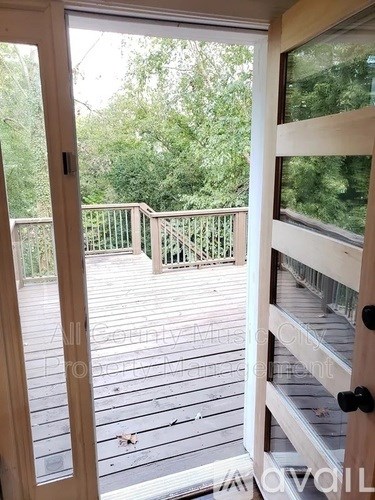 A deck with a railing and trees in the background.