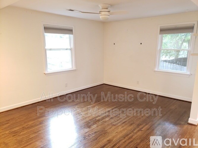 A room with wood flooring and two windows is available for rent.