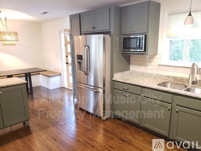 A kitchen with a refrigerator, microwave, and sink.