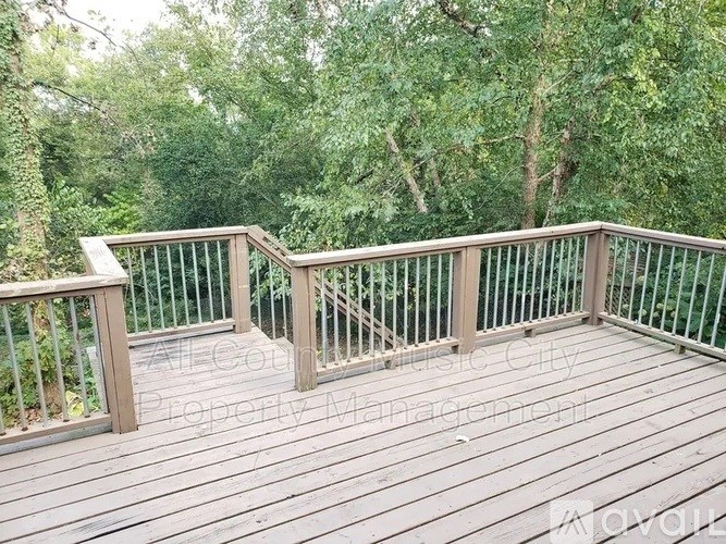 A wooden deck with a metal railing overlooks a green forest.