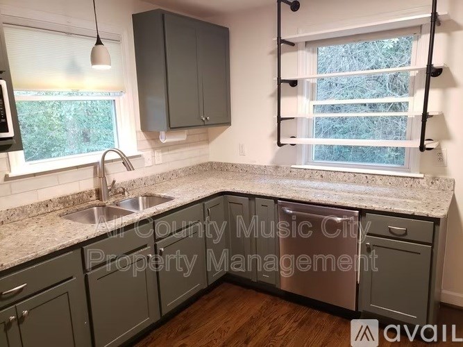 A kitchen with granite countertops and a window with blinds.