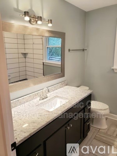 A bathroom with a marble countertop and a large mirror above the sink.