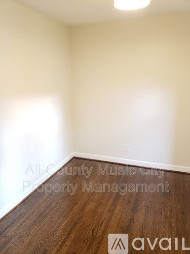 A room with wooden flooring and a white wall.