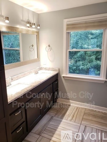 A bathroom with a large mirror and a window showing trees outside.