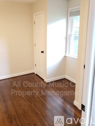 A room with a door and a window with a wooden floor.
