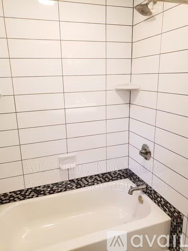 A white bathtub with a black and white tile border.