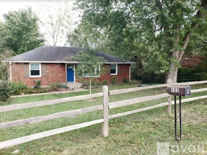 A small house with a blue door is surrounded by a white fence.