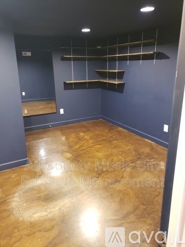 A room with wooden floors and shelves on the wall.