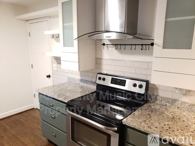 A kitchen with granite countertops and a stainless steel range hood.
