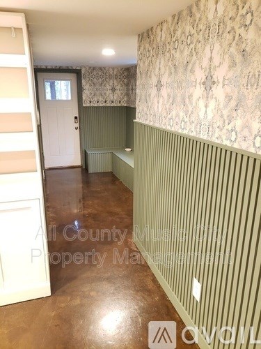 A room with a white door and a wallpapered wall.