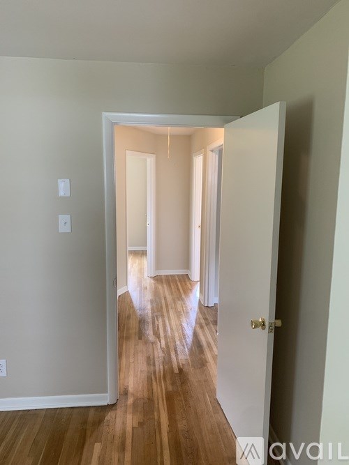 A hallway with a wooden floor and white walls.