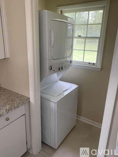 A white dishwasher is in a kitchen next to a window.