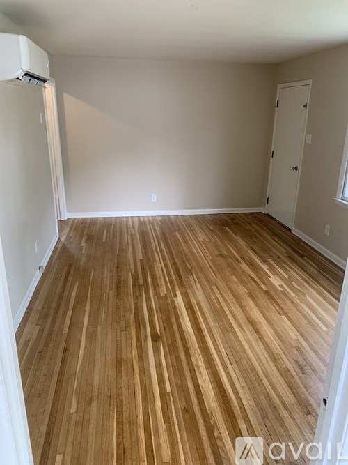 A room with wooden flooring and white walls.