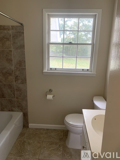 A bathroom with a toilet, tub, and window.
