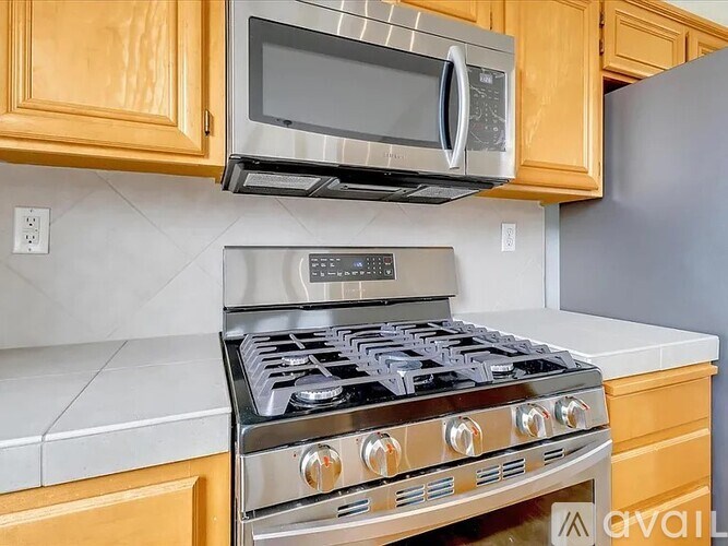 A modern kitchen with a stainless steel gas stove and a microwave above it.