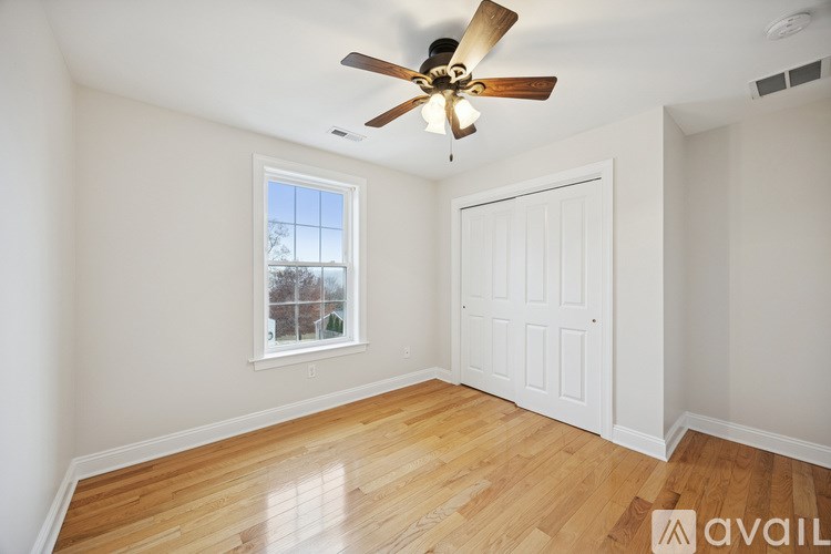 A grey house with a brown fence and a gravel driveway.