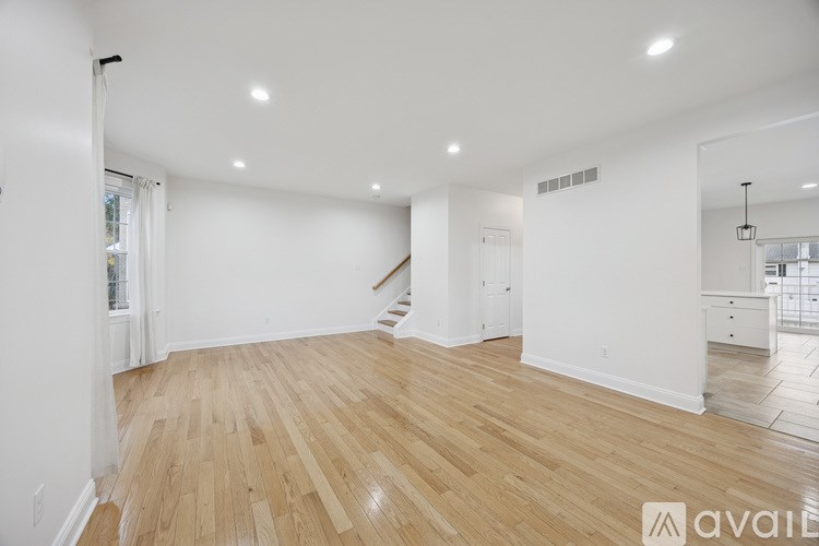 A spacious room with wooden flooring and white walls.