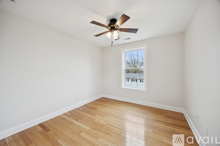 A room with a ceiling fan and wooden flooring.
