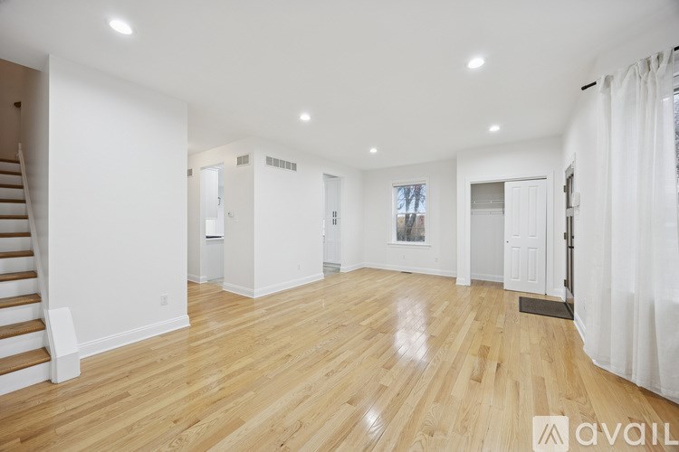 A spacious room with wooden flooring and white walls.