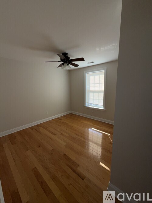 A room with a ceiling fan and wooden flooring.