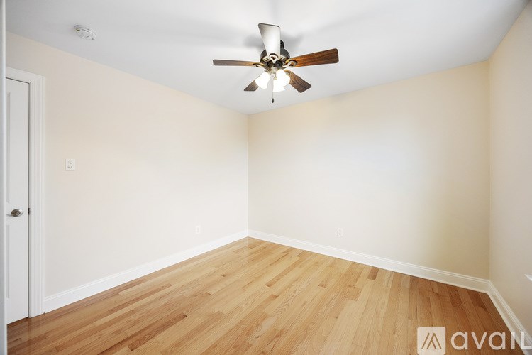 A room with a ceiling fan and wooden flooring.