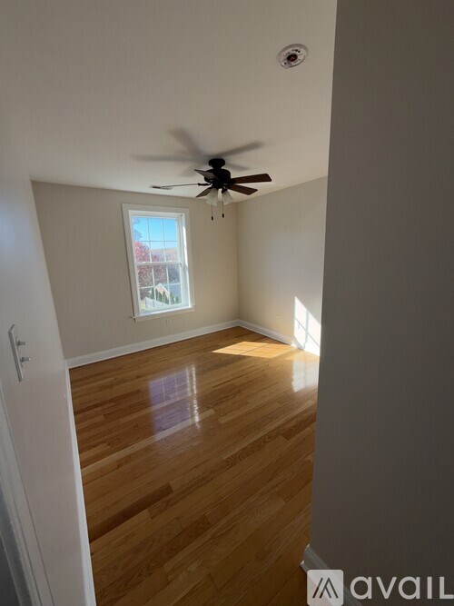 A room with a ceiling fan and wooden flooring.