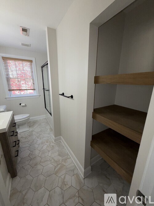 A bathroom with a toilet, sink, and shelves.