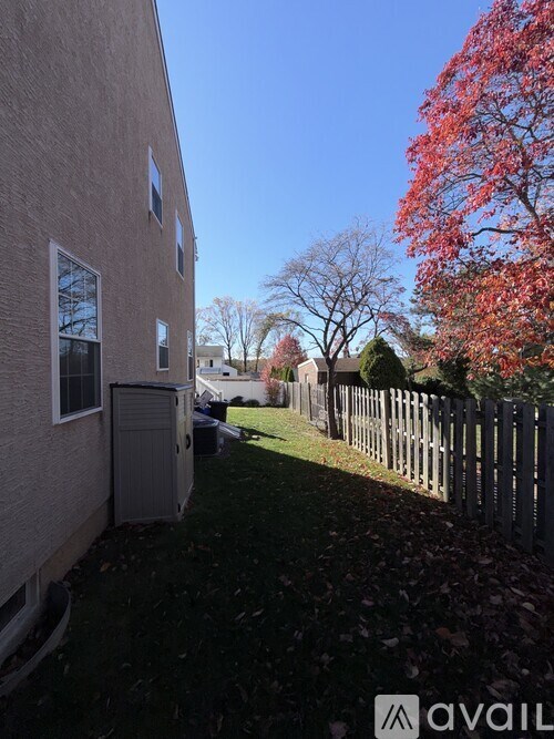 A tree with red leaves is next to a house.