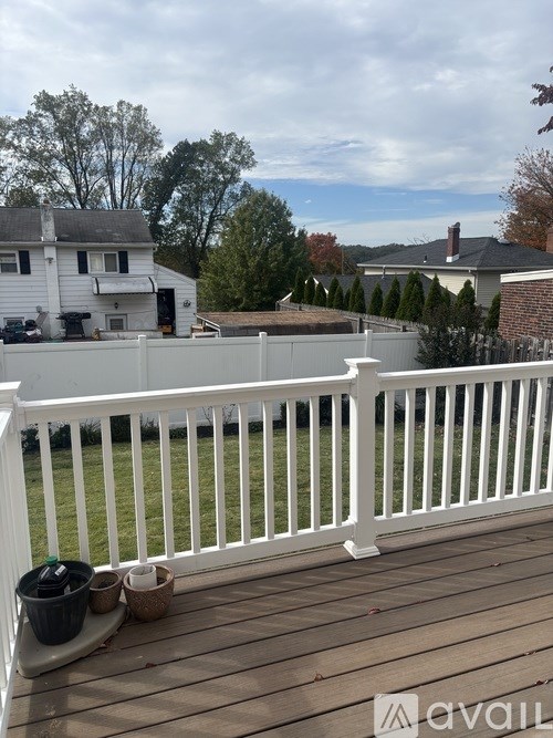 A deck with a white railing and a few potted plants.