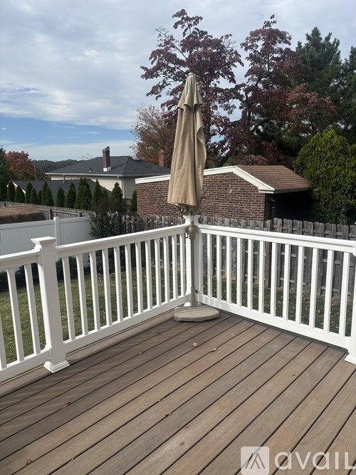A deck with a white railing and a tan umbrella.